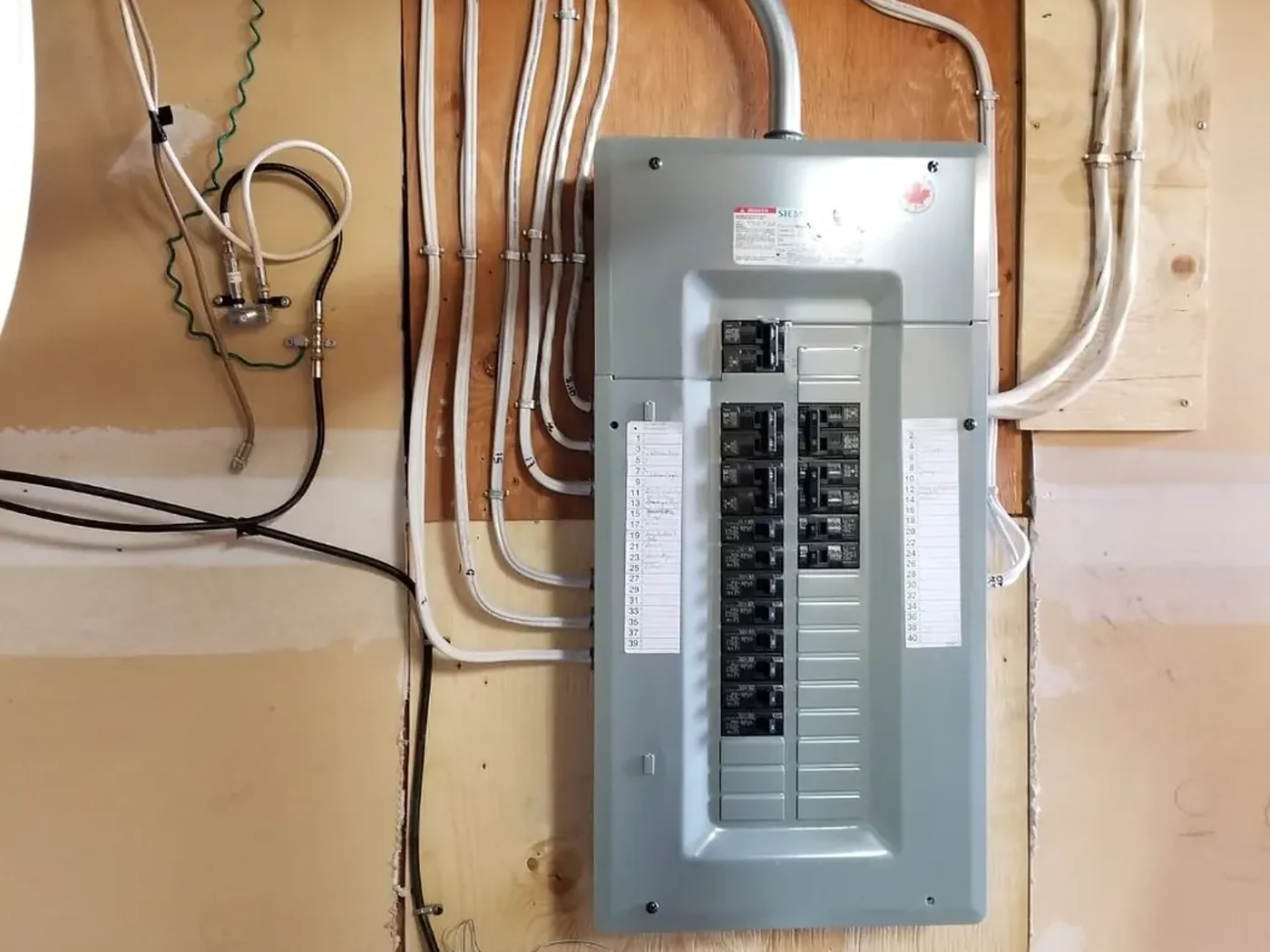 After: finished Siemens panel with a labelled circuit directory and tidy cable runs, same Edmonton wall