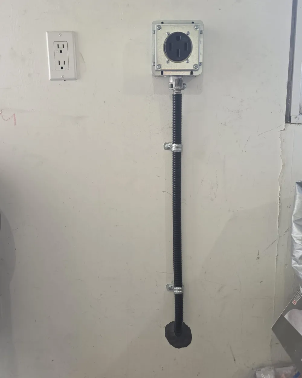 Weatherproof 240 volt EV charging receptacle mounted in a metal box on a garage wall in Edmonton.