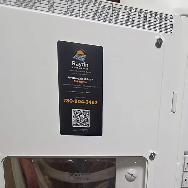 A Raydn Renewables card tucked inside the Leviton panel door