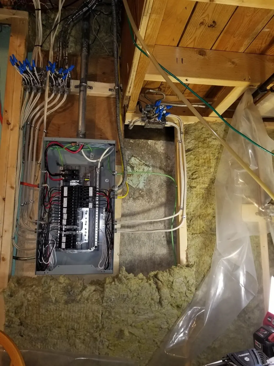 An Edmonton basement panel at rough in with the deadfront removed, breakers landed and every home run cable dressed up the stud in wire connectors
