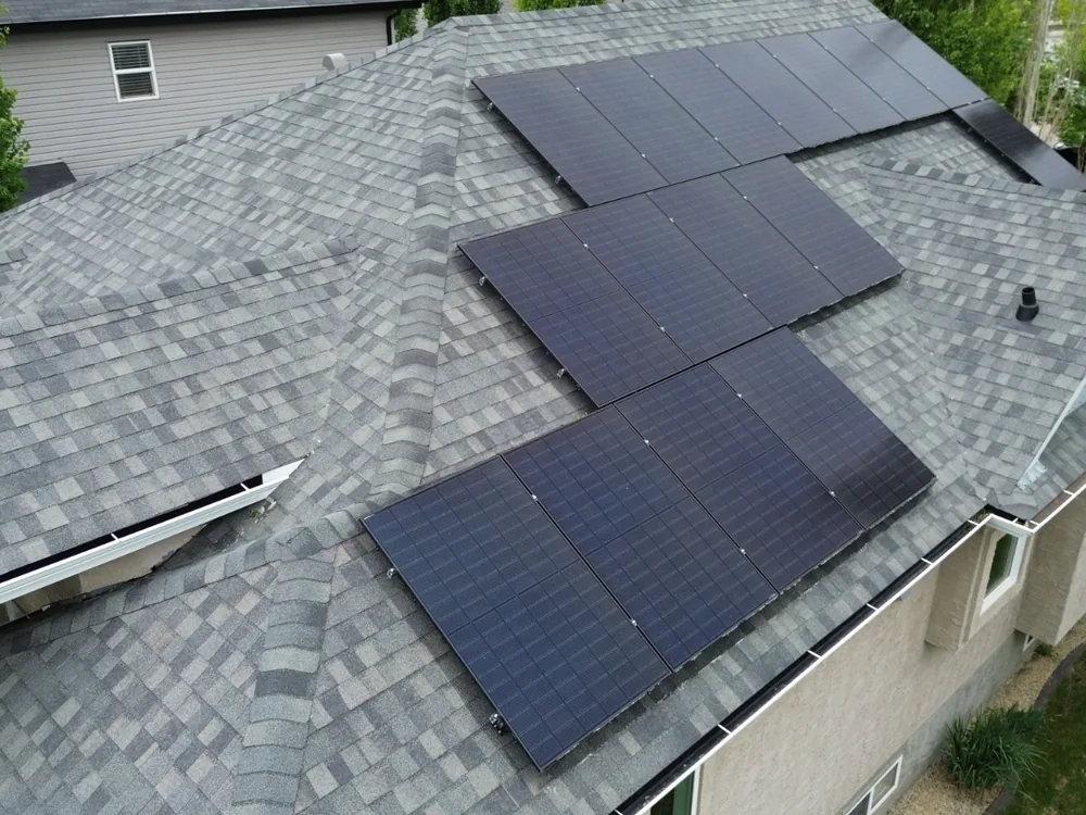 Aerial view of an all-black solar array across three roof sections on a St. Albert home