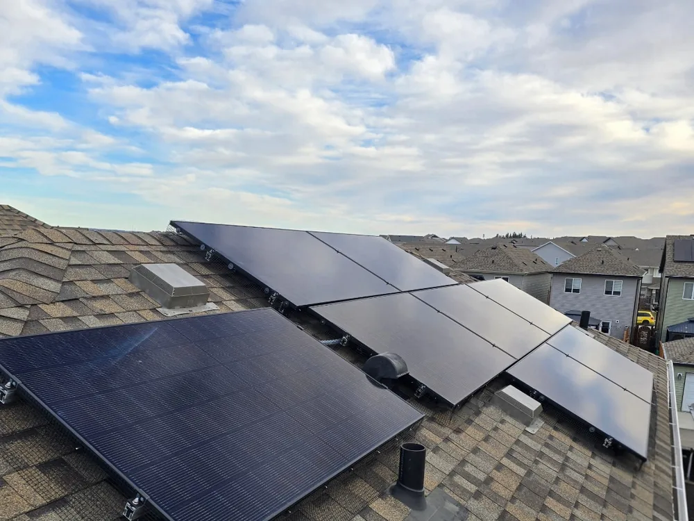 Black framed solar panels installed across multiple roof faces on an Edmonton home