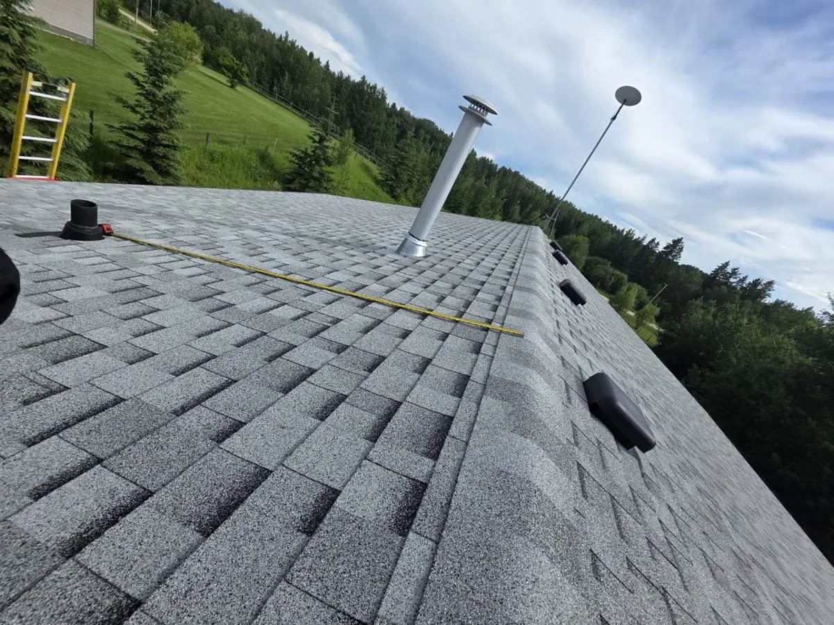 Master Electrician measuring roof shingle area with tape during solar site survey, Alberta