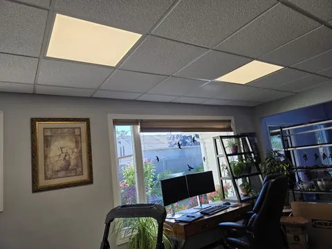 Upstairs office ceiling before the work, lit by two flat 2 ft by 2 ft LED panels.