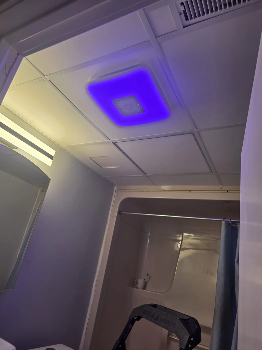 The same bathroom ceiling after the swap, with the new smart exhaust fan and light fitting lit.
