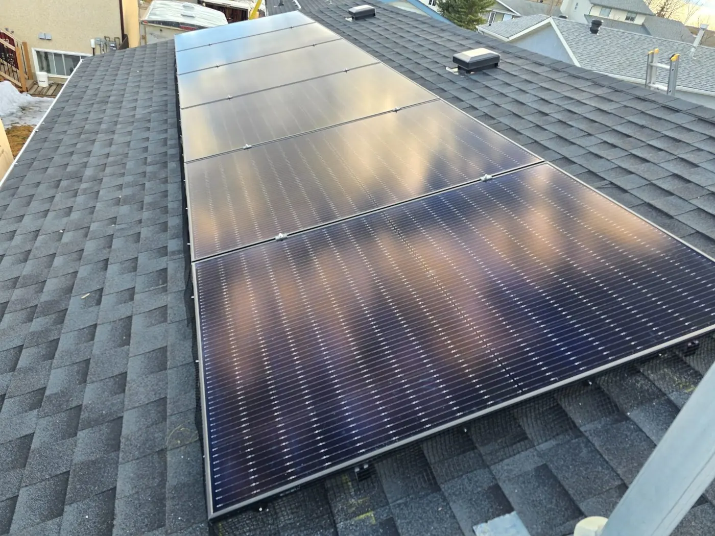 Completed black solar panels on dark grey shingle roof, close-up, Edmonton