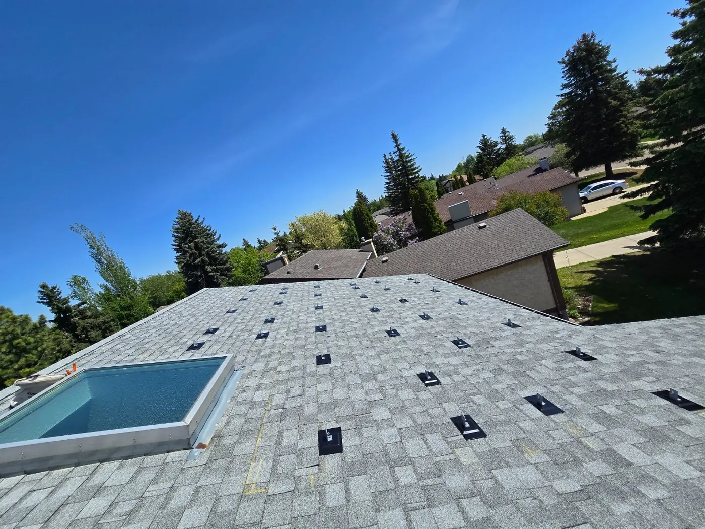 Light grey shingle roof with solar standoffs installed around skylight before panels, Edmonton