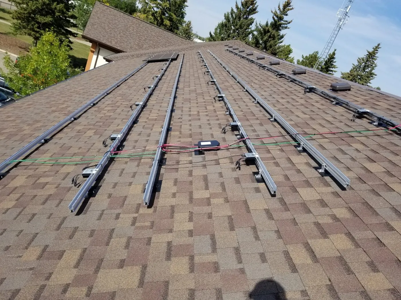 Solar panel mounting wiring on brown shingle roof Alberta
