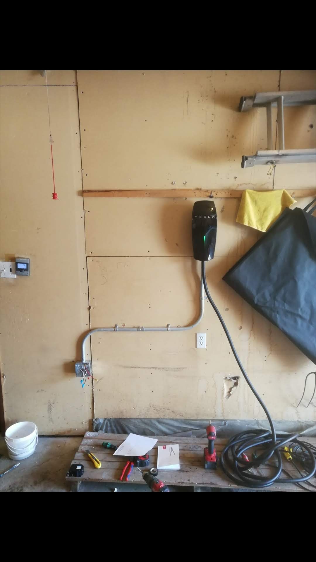 Tesla Wall Connector installed with a strapped conduit run in an Alberta garage by Raydn Renewables