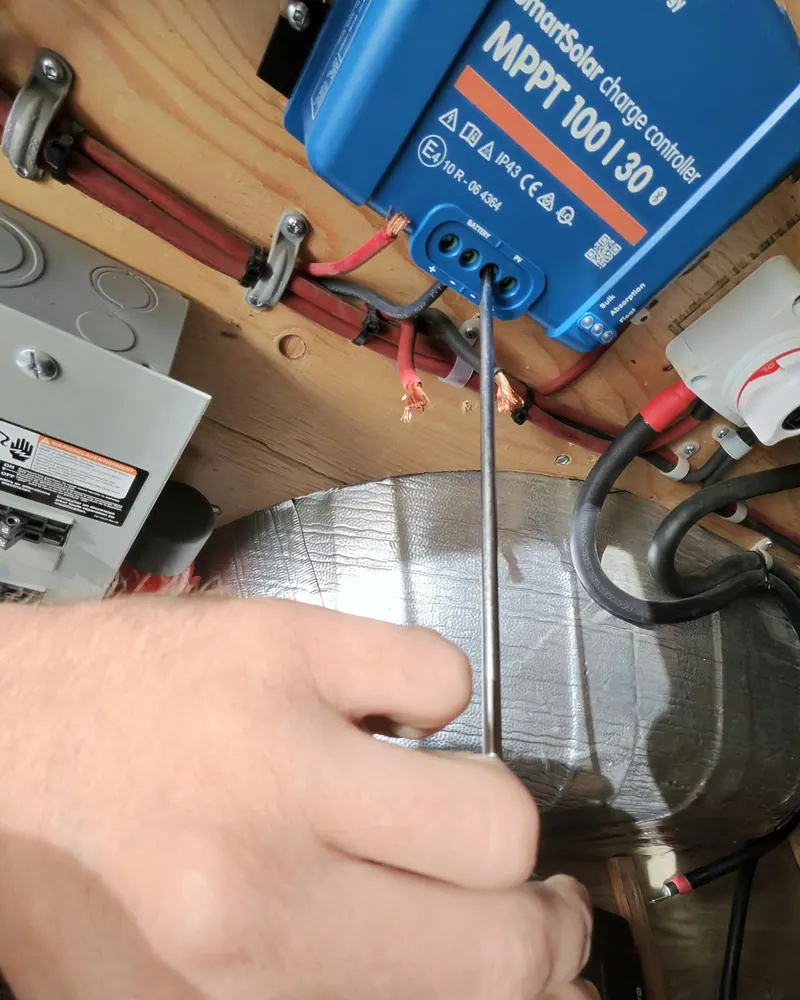 Screwdriver tightening a wire into a terminal on the new solar charge controller